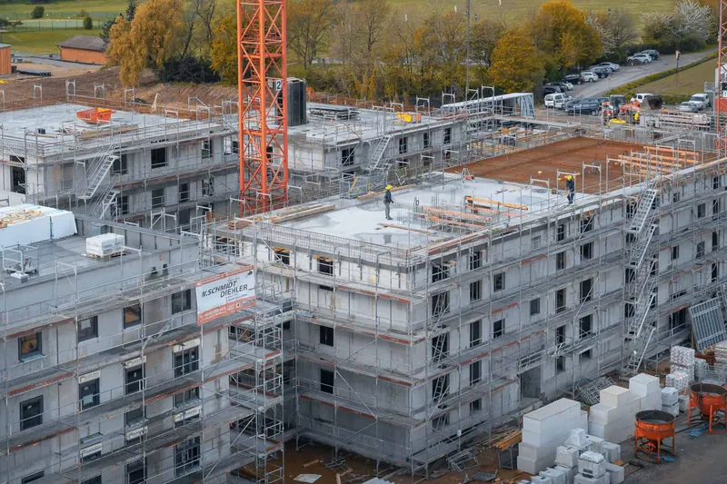 Wiesbaden-Delkenheim'da iskeleli çok katlı konut binalarının kaba inşaatı ve turuncu kule vinç